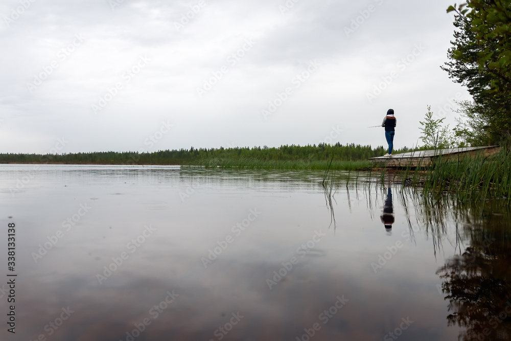 Finnish young woman fishing on the lake in a rainy day. Finnish young woman fishing on the lake in a rainy day.