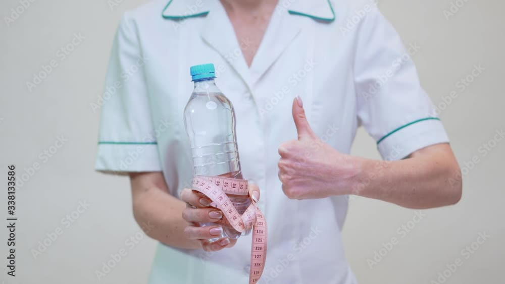 nutritionist doctor healthy lifestyle concept - holding bottle of water and measuring tape nutritionist doctor healthy lifestyle concept - holding bottle of water and measuring tape