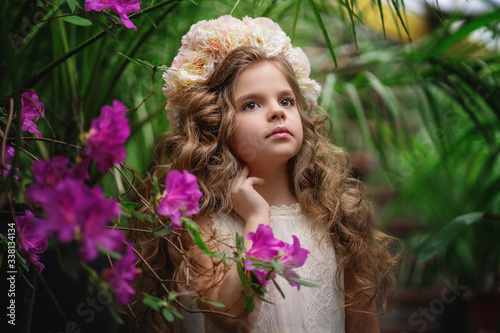 Little girl in blooming garden, enjoys spring and warmth. Happy childhood, peace and happiness concept