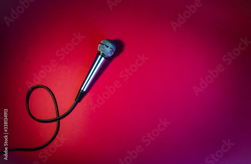 Silver microphone on a red background, with a black cord.