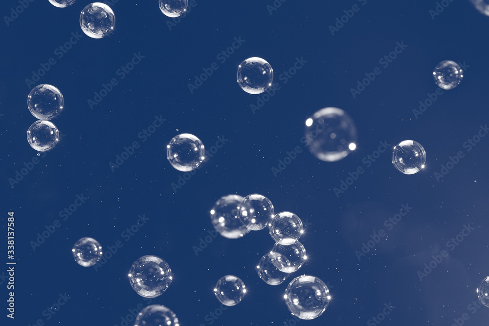 Flying soap bubbles isolated on blue background. Abstract background.