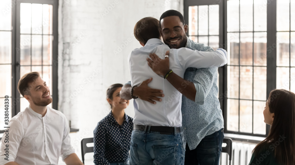 Happy diverse young people hug show support and understanding participate in counseling session together, smiling male patients embrace feel supportive engaged in psychological training or therapy Happy diverse young people hug show support and understanding participate in counseling session together, smiling male patients embrace feel supportive engaged in psychological training or therapy