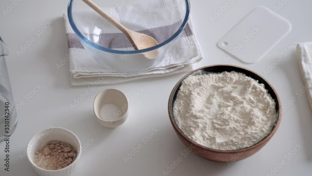 Shot of ingredients laid out for making bread. Water, salt, flour and yeast.