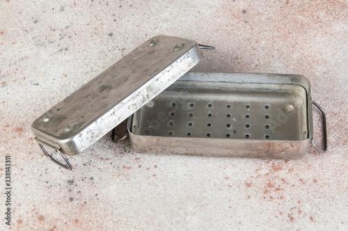 Old Soviet brass syringe sterilizer on concrete background.