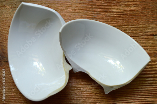 Broken white ceramic bowl on wooden background