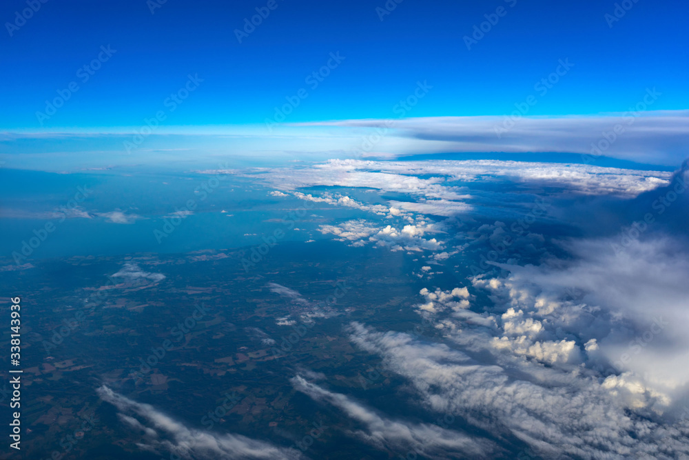 Clouds, earth, sky view from plane window in sunny day.