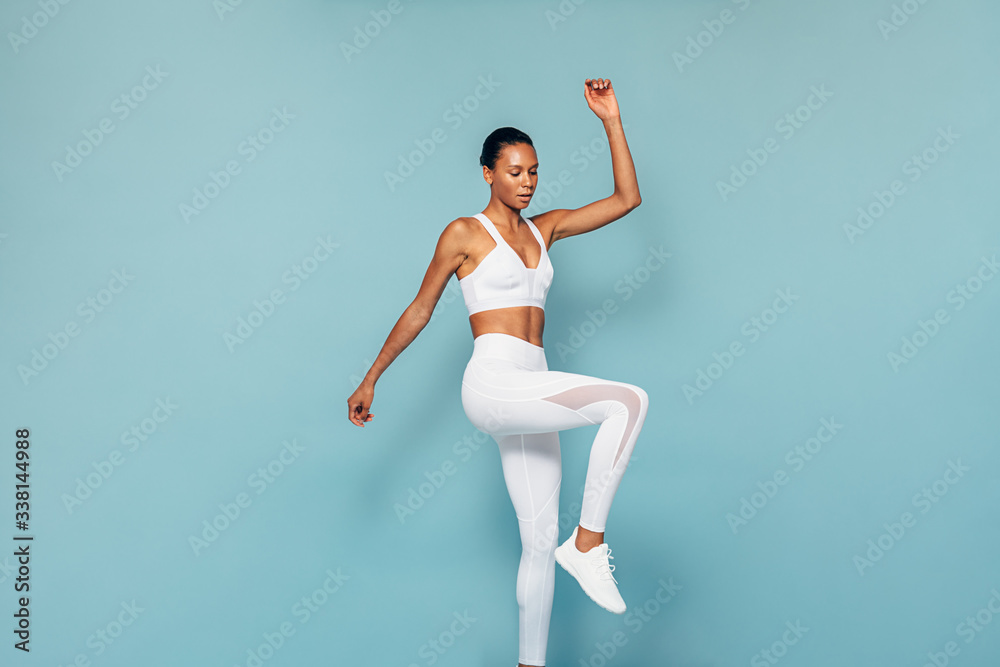 Young woman in sports wear warming up before training in studio