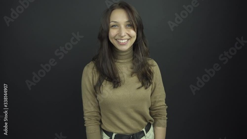 excited brunette in brown turtleneck smiles and shakes hands