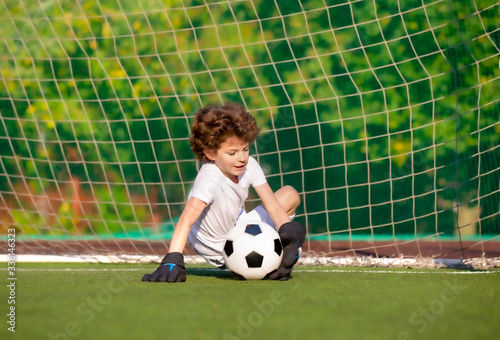 Summer soccer tournament for young kids. football club. emotions and joy of the game. Young goalie. Kids - soccer champion. Boy goalkeeper in football sportswear on stadium with ball. Sport concept. © kravik93