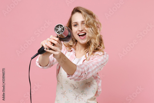 фотографія Cheerful funny young woman housewife in casual clothes, apron posing isolated on pastel pink wall background studio portrait
