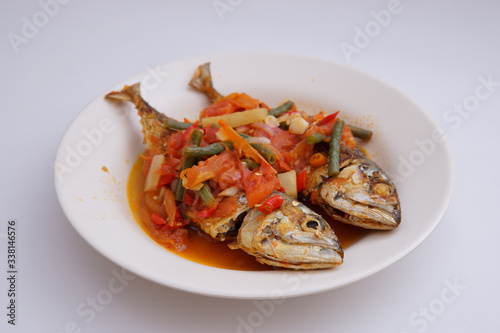 fried fish with chili sauce and tomatoes on top isolated white background