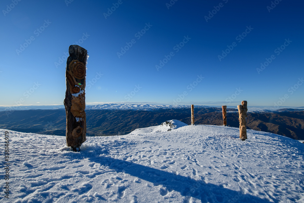 Snow peak with Maori poles in south island, Wanaka, New Zealand. Photograph in winter 2019. Snow peak with Maori poles in south island, Wanaka, New Zealand. Photograph in winter 2019.