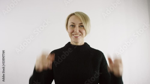 Adult middle aged caucasian blond short haired woman finger snapping with both hands against white background in bright interior