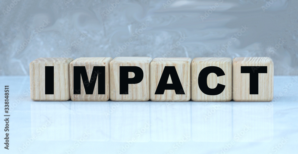 concept word IMPACT on wooden cubes on a beautiful gray background concept word IMPACT on wooden cubes on a beautiful gray background
