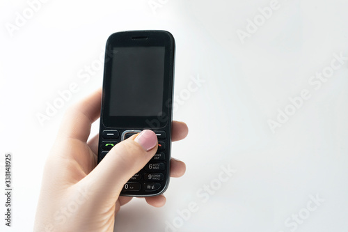 Push-button telephone in a female hand on a white background
