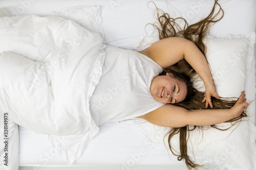 Photos Portrait of a happy excited confident positive cheerful plump woman with dark hair in bed