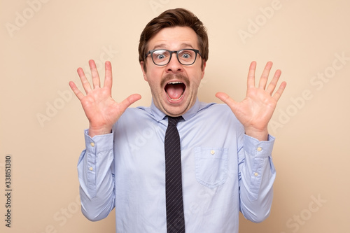 Excited happy dult male with moustache raising palms showing ten fingers photo