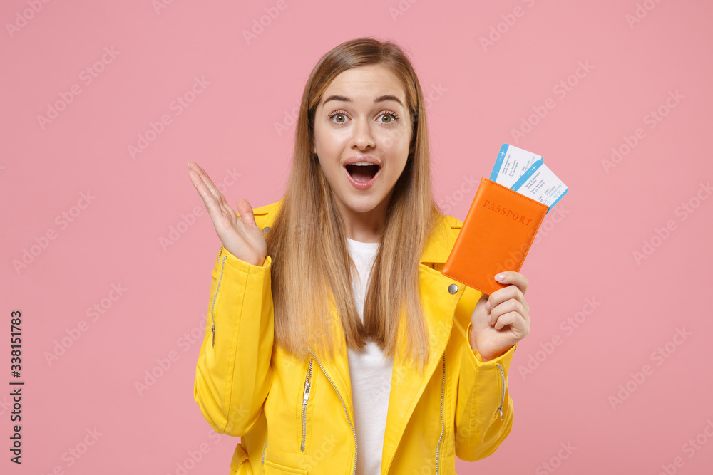 Excited young woman girl in yellow leather jacket posing isolated on pastel pink background studio. People lifestyle concept. Mock up copy space. Hold passport tickets boarding pass, spreading hands. Excited young woman girl in yellow leather jacket posing isolated on pastel pink background studio. People lifestyle concept. Mock up copy space. Hold passport tickets boarding pass, spreading hands.