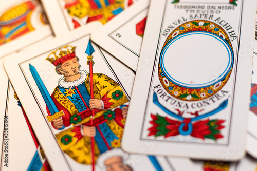 Triestine cards, old european game originating from northern italy laying on the wooden table. Flat lay with ace and king of denars in focus, italian language on the card