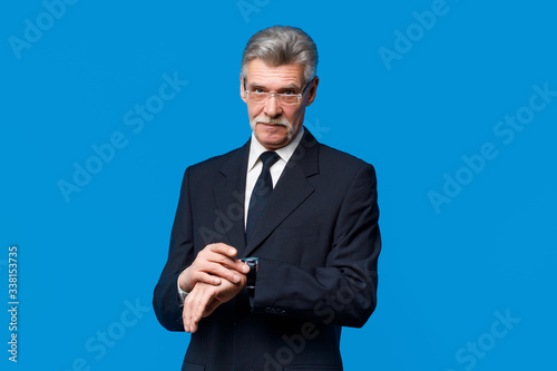 Photo of a handsome smiling older businessman dressed inblack suit  standing isolated over blue background photo