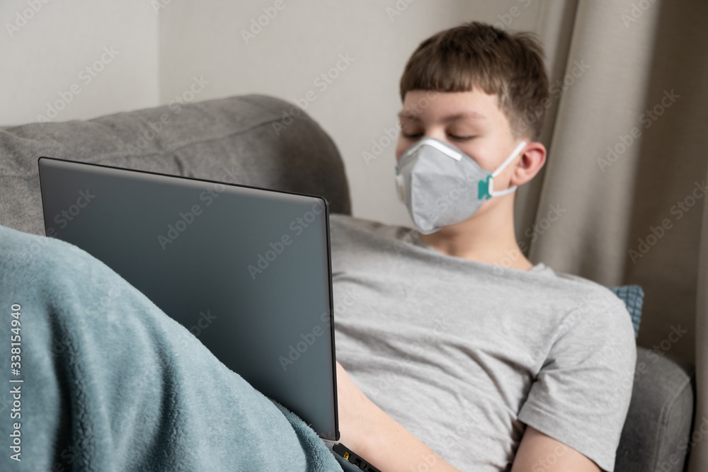 Teenager pass online education on laptop at home in medical mask against virus Covid 19. Prevention of Coronavirus. Teenager pass online education on laptop at home in medical mask against virus Covid 19. Prevention of Coronavirus.