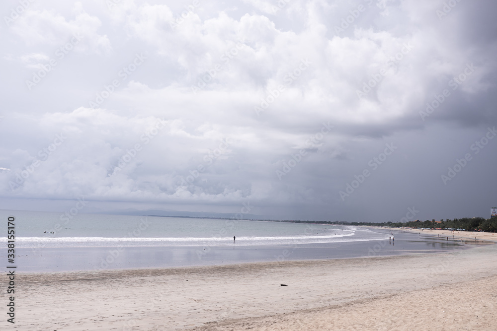 Deserted beach on the island of Bali. Clouds and clouds with rain of dark blue color. Sandy beach with sea and ocean. Tropical view. Hurricane.