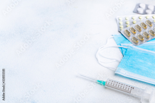 Medical protective masks, disposable syringe and pharmaceutical packaging with pills on white background. The concept of protecting health from the virus.