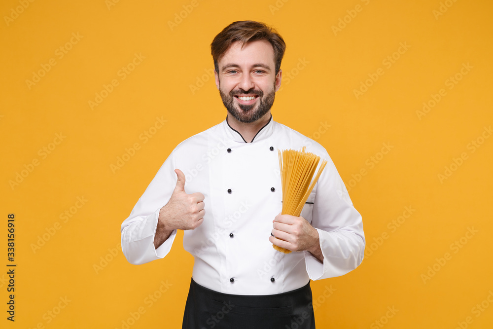Smiling young bearded male chef cook or baker man in white uniform shirt posing isolated on yellow wall background. Cooking food concept. Mock up copy space. Hold spaghetti pasta, showing thumb up. Smiling young bearded male chef cook or baker man in white uniform shirt posing isolated on yellow wall background. Cooking food concept. Mock up copy space. Hold spaghetti pasta, showing thumb up.