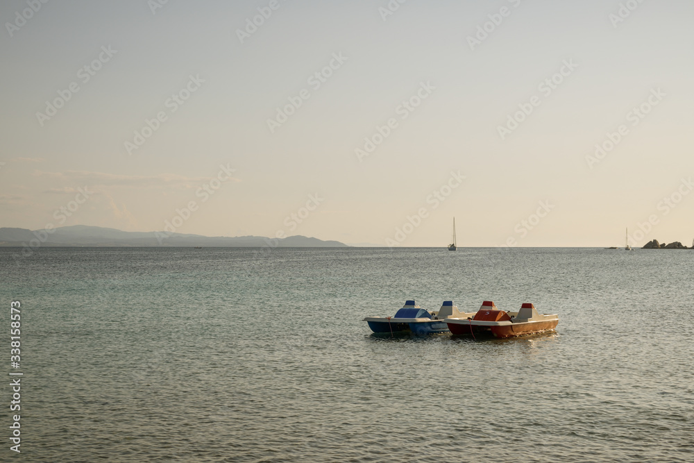 Two pedal boats floating on water in bay close to Capo Testa in Sardinia,