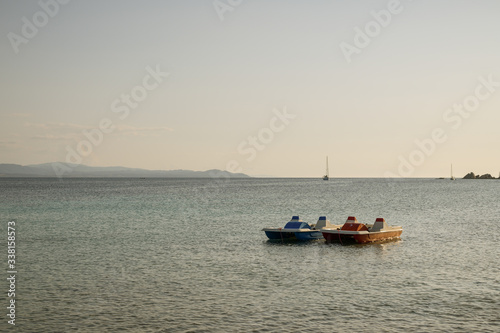 Two pedal boats floating on water in bay close to Capo Testa in Sardinia, © Michal