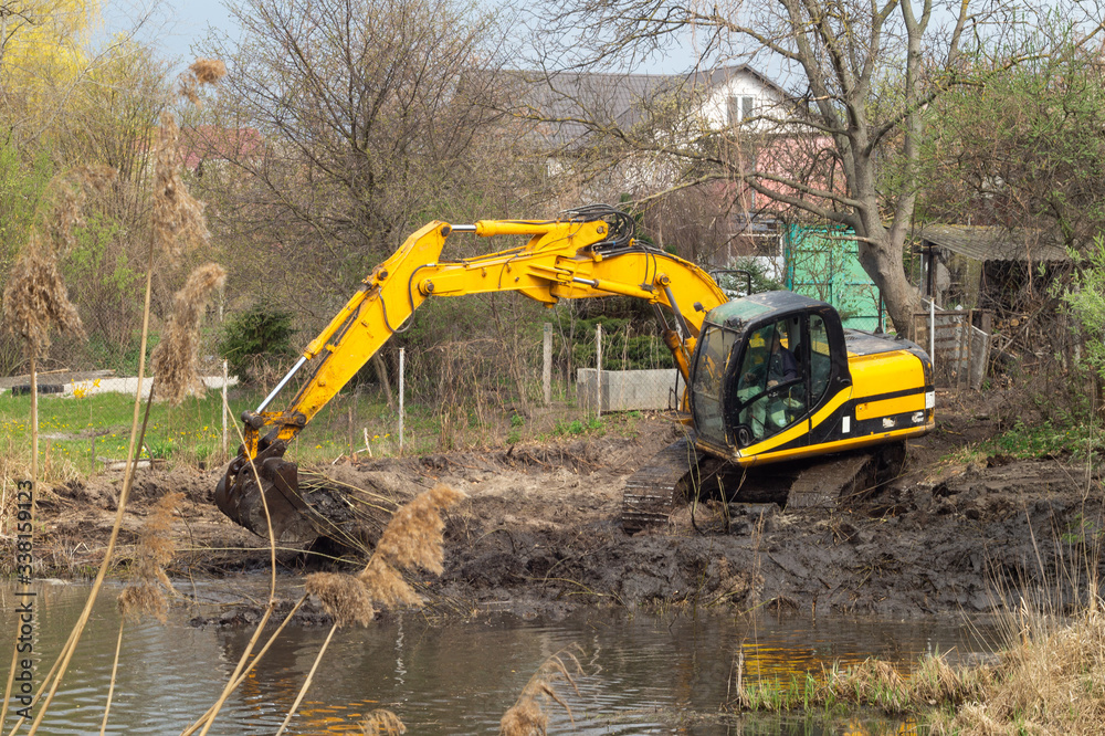 Crawler excavator or digger dredges on the lake Crawler excavator or digger dredges on the lake