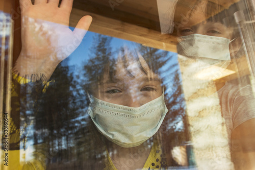 Close-up of little girls looking out of the window. Children are being quarantined because of the coronavirus epidemic.