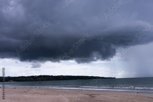 Deserted beach on the island of Bali. Clouds and clouds with rain of dark blue color. Sandy beach with sea and ocean. Tropical view. Hurricane.
