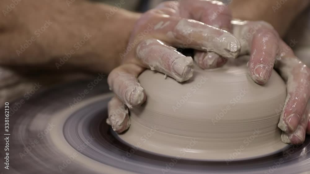 Experienced hands of a potter on a pottery wheel close-up making flat and wide plate. Old traditional art, handmade, ceramic production Experienced hands of a potter on a pottery wheel close-up making flat and wide plate. Old traditional art, handmade, ceramic production