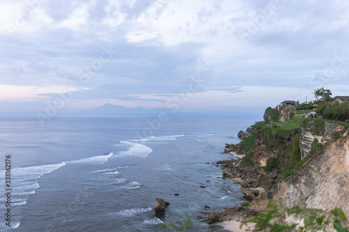 Beautiful blue sunset on the ocean with big waves and cliffs and cliffs. Bali island with its tropical and exotic nature. Sunrise over the sea and ocean. Phantom blue in sunset