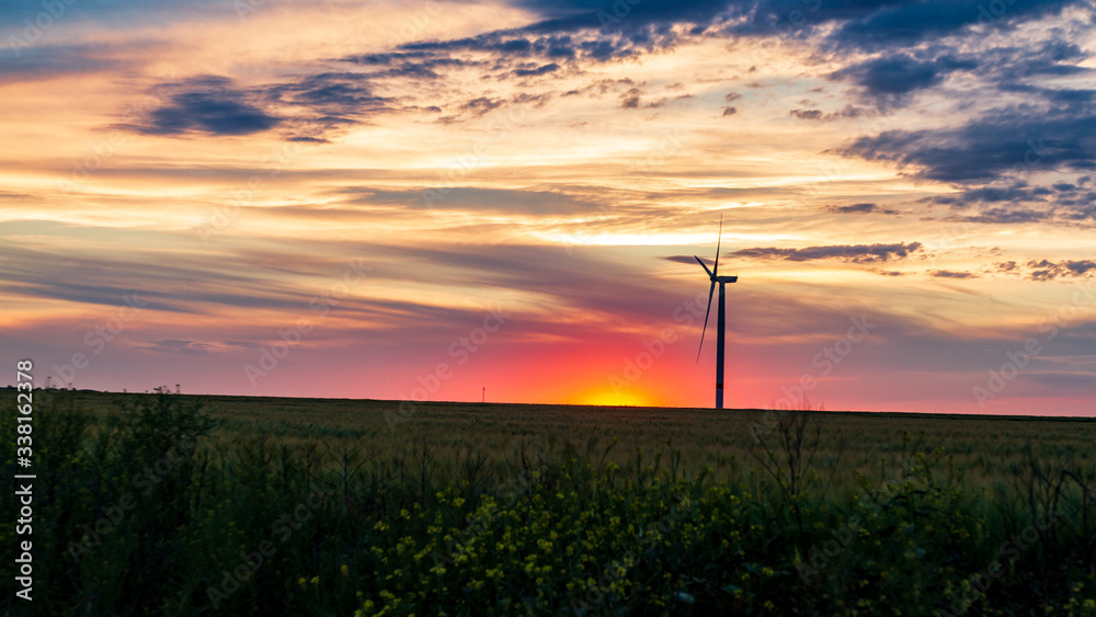 Obraz premium wind generator in grass field at sunset