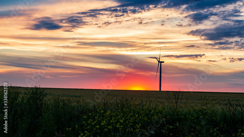 wind generator in grass field at sunset