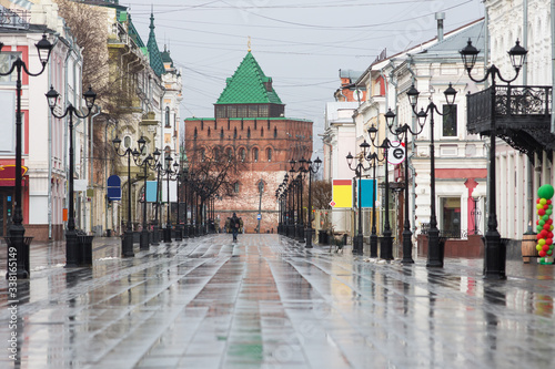 Fototapeta Naklejka Na Ścianę i Meble -  Bolshaya Pokrovskaya street in Nizhny Novgorod without people after rain with reflections of buildings on the paving stones in the rays of the spring sun