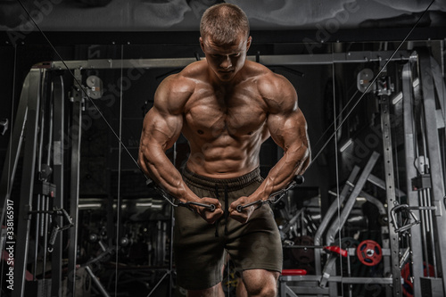 Portrait of handsome sporty man with naked muscular torso doing weight lifting