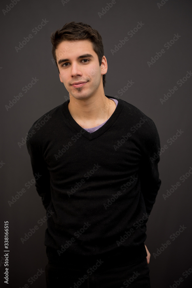 Handsome white young male model with short hair, and black sweater with arms behind