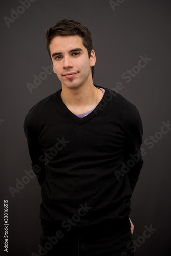Handsome white young male model with short hair, and black sweater with arms behind