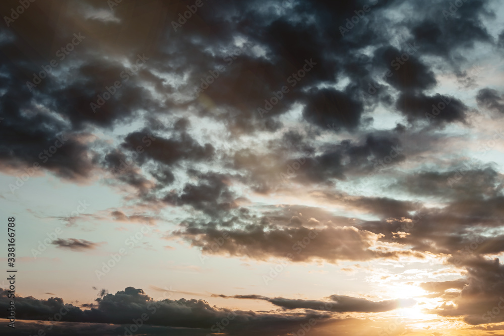 Dramatic Sky at Sunset with Dark Stormy Clouds and Rays of Sun. Lens Flare on Twilight Bright Sky. Sombre Sky Background. Contrasting Sunrise Scene. Sunshine. Landscape of Dusk