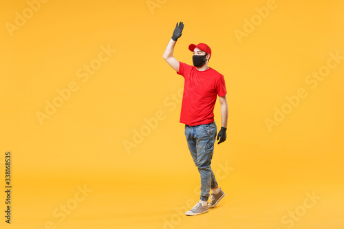 Full length delivery man in red cap t-shirt uniform sterile face mask gloves isolated on yellow background studio Guy employee courier Service quarantine pandemic coronavirus virus 2019-ncov concept.