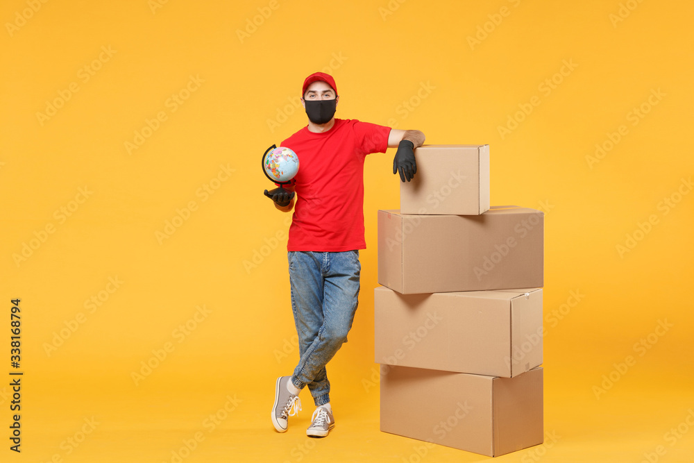 Delivery man employee in red cap blank t-shirt uniform face mask glove hold empty cardboard box isolated on yellow background studio Service quarantine pandemic coronavirus flu virus 2019-ncov concept Delivery man employee in red cap blank t-shirt uniform face mask glove hold empty cardboard box isolated on yellow background studio Service quarantine pandemic coronavirus flu virus 2019-ncov concept