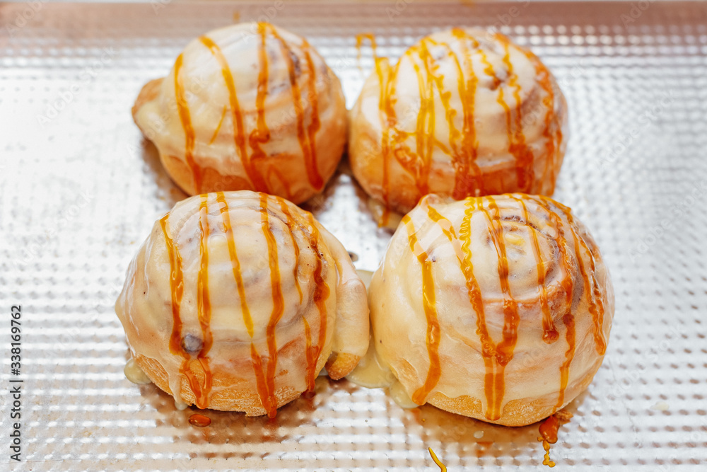 Preparation of homemade cakes. The girl spreads the cream on the pastry. Cinnabon. View from above. Rustic. Close-up. Preparation of homemade cakes. The girl spreads the cream on the pastry. Cinnabon. View from above. Rustic. Close-up.