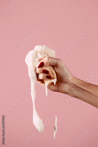 ice cream is melting in hand, fist squeezes ice cream on a pink background