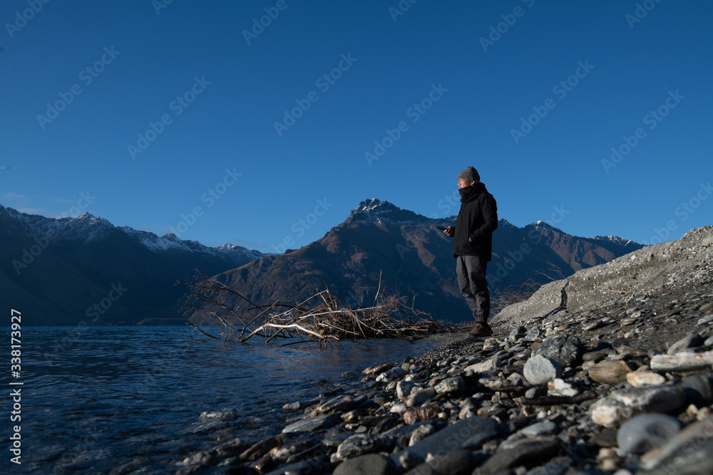 Asian man stand at the front of beautiful view close to the lake with sunrise in New Zealand.