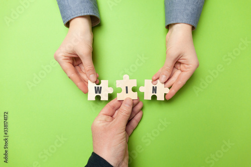 Hands of businessman hold puzzles with the inscription "WIN". Bringing people together for success and victory.