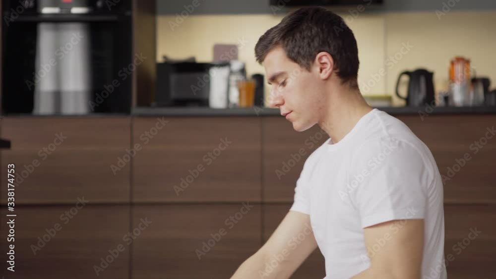 Tilt up side view of young man applying hand sanitizer spray while using web search engine on laptop computer sitting on floor at home Tilt up side view of young man applying hand sanitizer spray while using web search engine on laptop computer sitting on floor at home