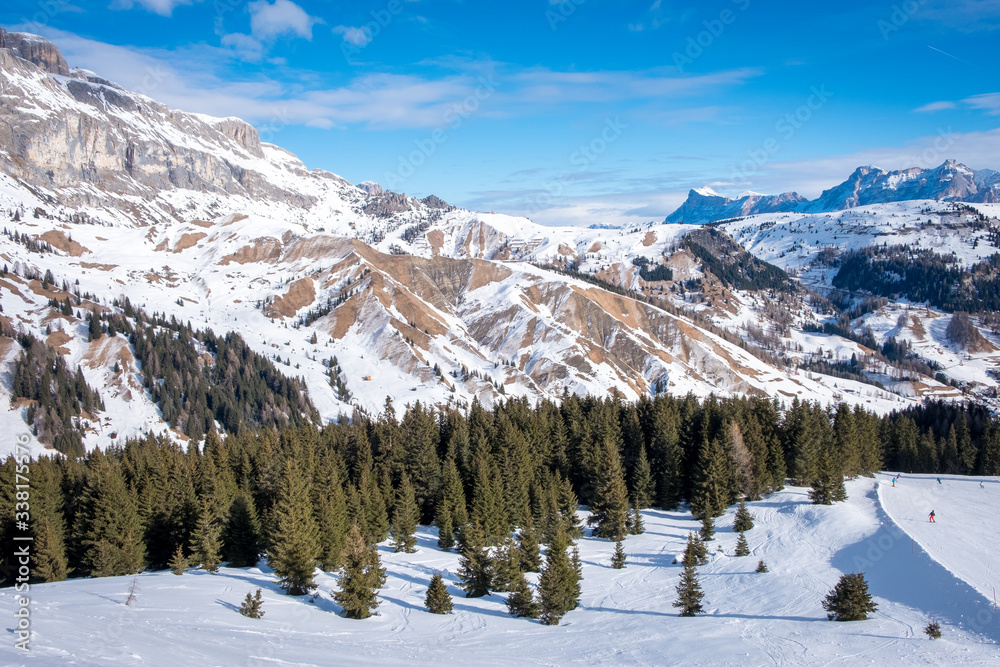 View of coniferous forest and mountains from a chair lift on a sunny winter day. Ski resort Arabba in Dolomites mountains. Passo Pordoi pass. , Italy